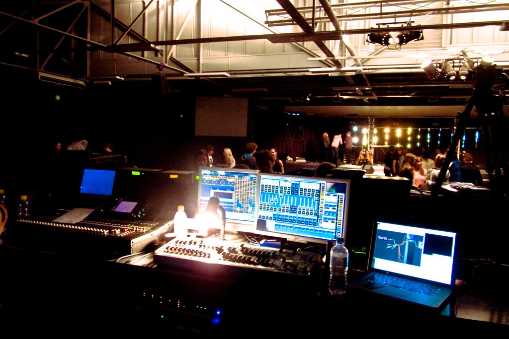 computer screens, a laptop, and a 48 fader 2-scene preset console